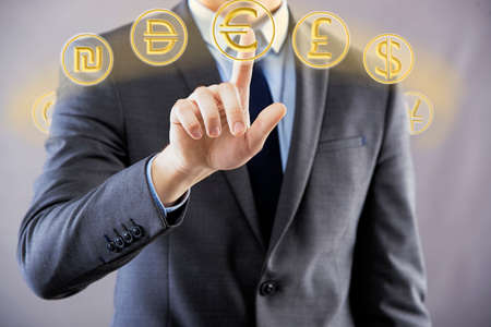 Man pressing buttons with different currenciesの写真素材