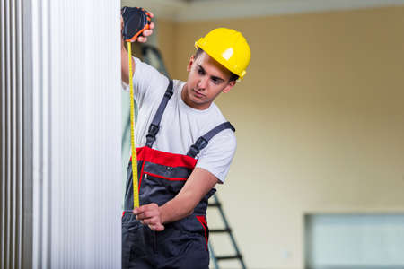 Young repairman with tape measure working on repairsの写真素材