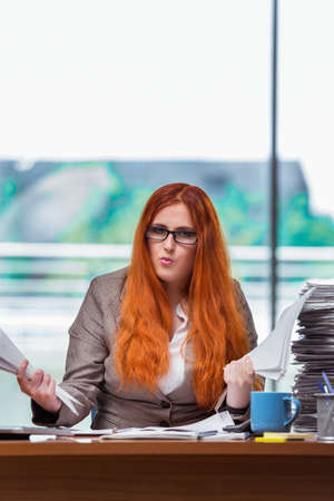 Stressed businesswoman with stack of papersの写真素材