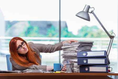 Stressed businesswoman with stack of papers