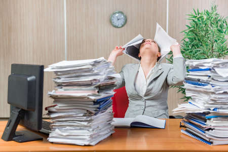 Woman under stress from excessive paper workの写真素材