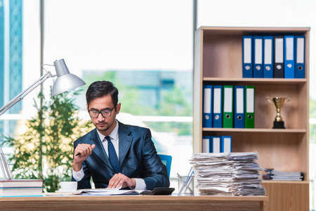 Young businessman in stress with lots of paperworkの写真素材