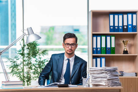 Young businessman in stress with lots of paperworkの写真素材