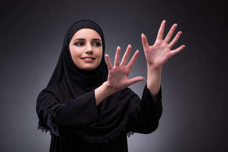Muslim woman in black dress against dark backgroundの写真素材