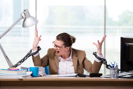 Woman chained to her working deskの写真素材