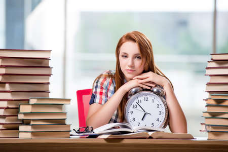 Female student with clock preparing for examsの写真素材