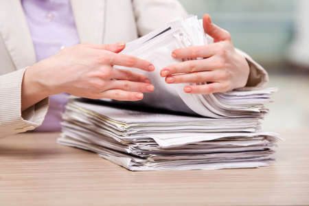 Businesswoman working with stack of papersの写真素材