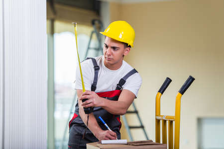 Delivery man taking dimensions with tape measure