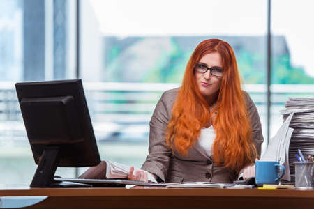 Stressed businesswoman with stack of papersの写真素材