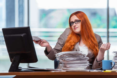 Stressed businesswoman with stack of papersの写真素材