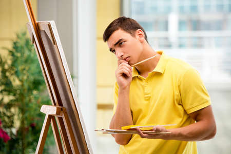 Young male artist drawing pictures in bright studioの写真素材