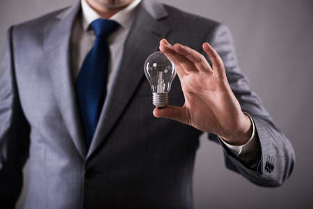 Businessman holding light bulb in creativity conceptの写真素材