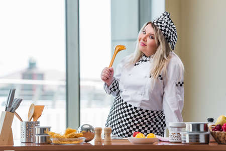 Female cook preparing soup in brightly lit kitchenの写真素材