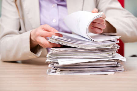 Businesswoman working with stack of papersの写真素材