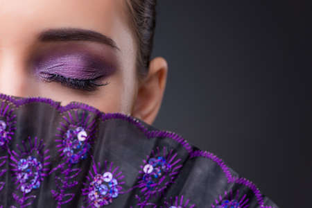 Nice woman with fan against gray backgroundの写真素材