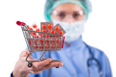 Doctor with shopping cart full of pills isolated on whiteの写真素材