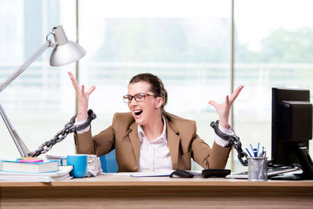 Woman chained to her working deskの写真素材