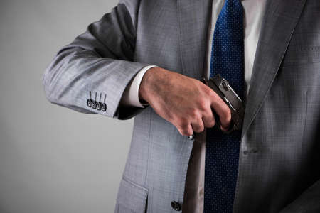 Man pulling out gun from his pocketの写真素材