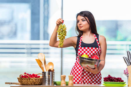 Young cook with fruits in the kitchenの写真素材