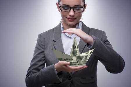 Businesswoman with dollar boats in business conceptの写真素材
