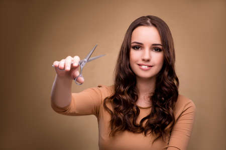 Beautiful woman with scissors cutting her hairの写真素材