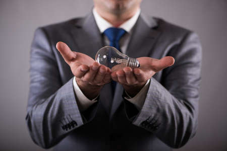Businessman holding light bulb in creativity conceptの写真素材
