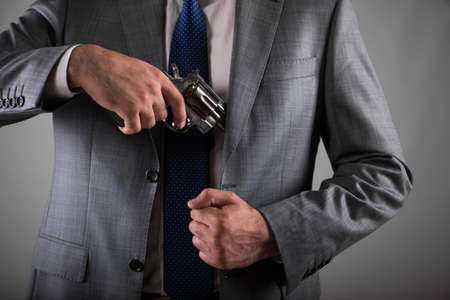 Man pulling out gun from his pocketの写真素材