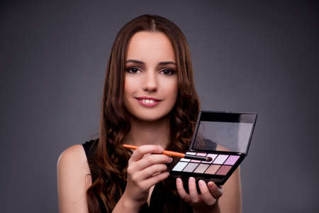 Beautiful woman applying make-up in fashion concept