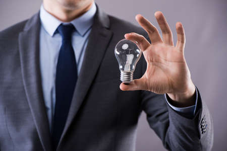 Businessman holding light bulb in creativity conceptの写真素材