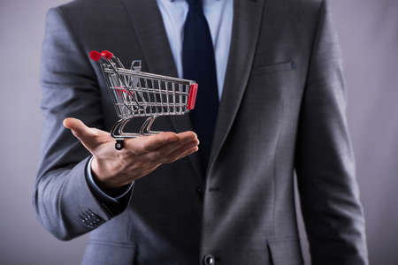 Buisinessman holding shopping cart in online shopping conceptの写真素材