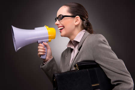 Young businesswoman with loudspeaker in business conceptの写真素材