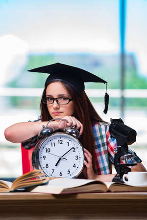 Young girl preparing for exams with large clockの写真素材
