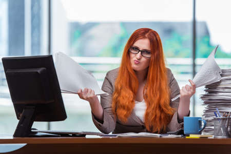 Stressed businesswoman with stack of papersの写真素材