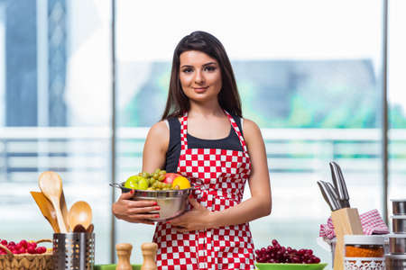 Young cook with fruits in the kitchenの写真素材