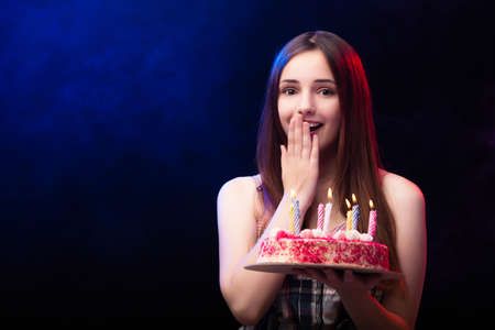 Young woman with birthday cake at partyの写真素材