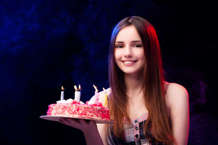 Young woman with birthday cake at partyの写真素材