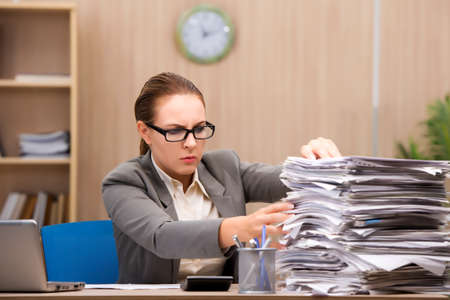 Businesswoman under stress from too much work in the officeの写真素材