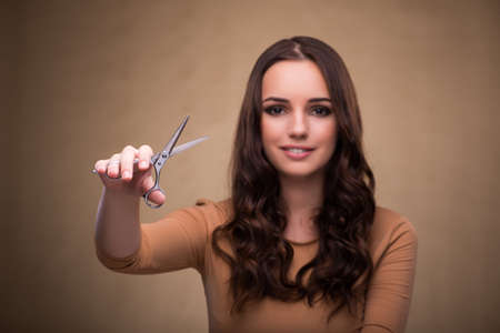 Beautiful woman with scissors cutting her hairの写真素材