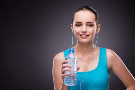 Woman doing sports with bottle of fresh waterの写真素材