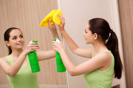 Young woman cleaning mirror at homeの写真素材