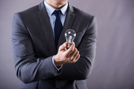 Businessman holding light bulb in creativity conceptの写真素材