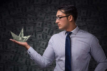 Businessman holding dollar paper boatsの写真素材