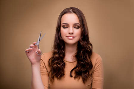 Beautiful woman with scissors cutting her hairの写真素材