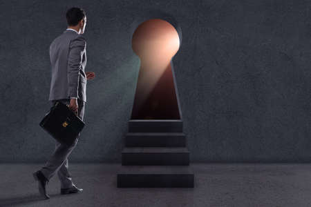 Businessman walking towards light from keyholeの写真素材