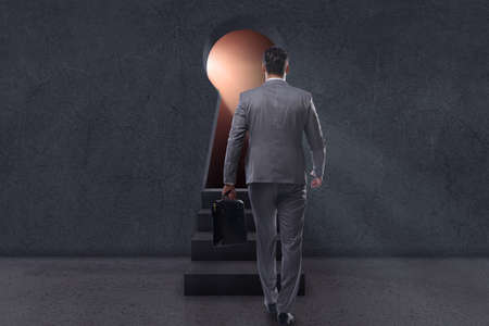 Businessman walking towards light from keyholeの写真素材