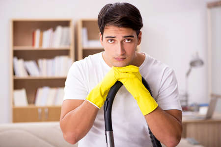 Man cleaning home with vacuum cleanerの写真素材