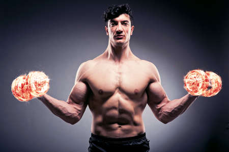 Muscular ripped bodybuilder with burning dumbbellsの写真素材
