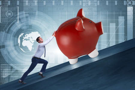 Man pushing piggybank uphill in business conceptの写真素材