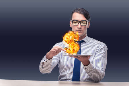 Businessman holding burning american dollar signの写真素材
