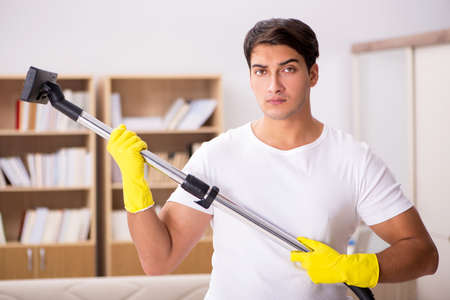 Man cleaning home with vacuum cleanerの写真素材